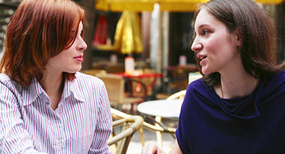 A photo of two women chatting in a café. 