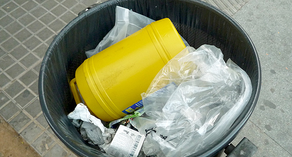 A photo of rubbish in rubbish bin in the street. 
