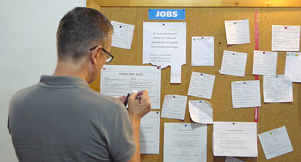 A photo of a person looking at job advertisements on a noticeboard.