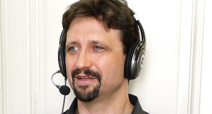 A photo of an online tutor, a man wearing headphones and a microphone. 