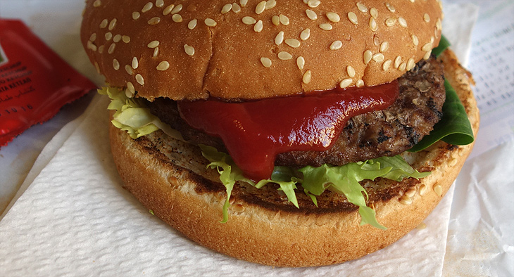 A photo of a hamburger with ketchup and lettuce. 