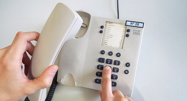 A photo of a person dialing on an office phone.