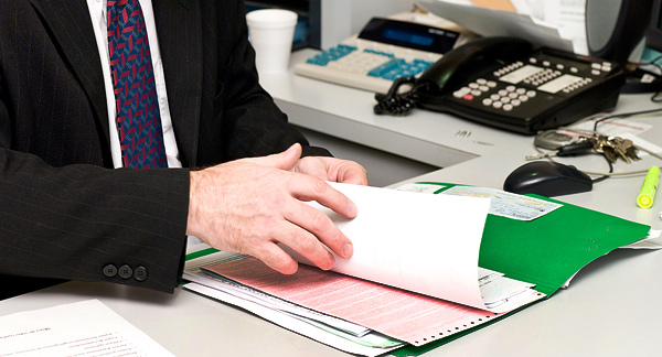 A photo of an officer worker looking at documents on a work desk. 