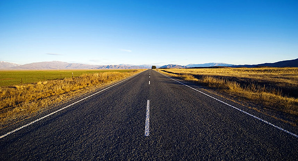 A photo of a highway stretching into the distance with mountains on the horizon. 