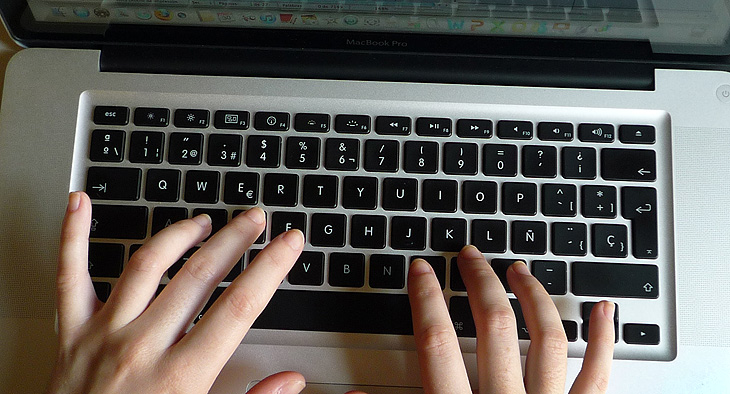 A photo of hands typing on a laptop computer.