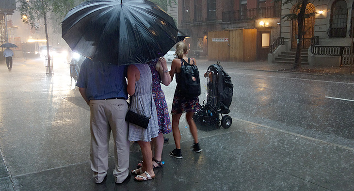 A photo of a family under an umbrella. It is raining.