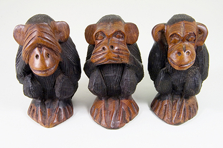 A photo of three monkeys carved out of wood. On monkey is covering its eyes, one is covering its mouth and one is covering its ears. 