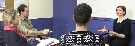 A photo of a tutor talking to tutorial students sitting in a circle. 