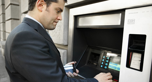 A photo of a person withdrawing money from an ATM.