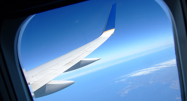 A photo taken from the window of a flying plane, looking over the wing.