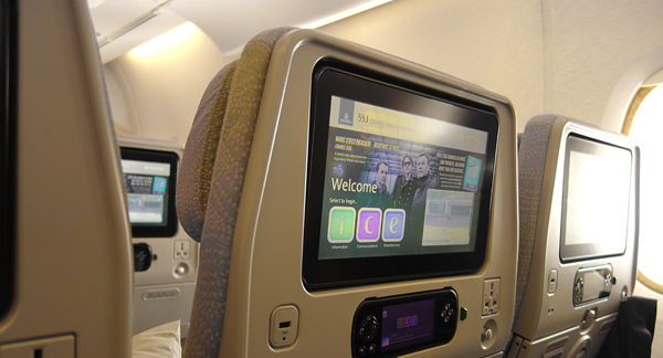 A photo of the interior of a plane, showing the seat and entertainment screen.
