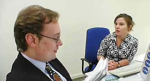 A photo of two people in an office making social conversation.