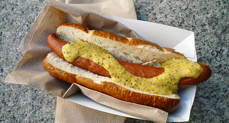 A photo of a hotdog with mustard, in a fast food container. 
